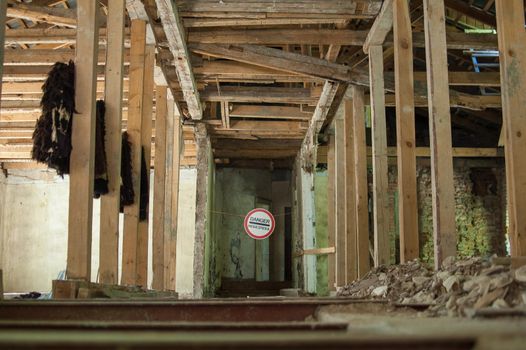 Old wrecked house with 'Danger' in English and in Ukrainian warning sign, abandoned building, uninhabitable place.