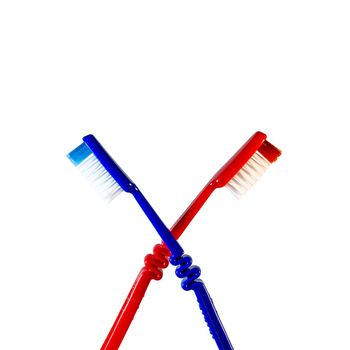 Two toothbrushes crossed on a white background. Blue and red toothbrushes

