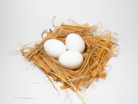 A chicken egg lies in the straw. Three eggs
