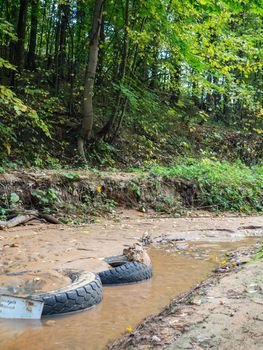 Tires in the sand at the bottom of the stream. Bad ecology