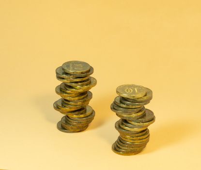 Two turrets made of coins. Money on yellow background
