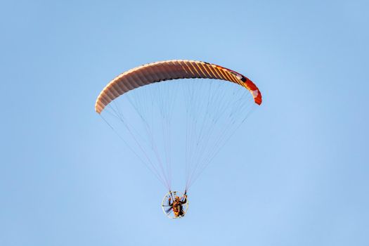 Powered paragliding flight against blue sky.