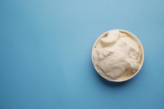 top view of milk cream in a container on blue background
