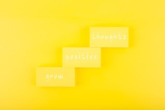 Positive affirmation, mental health or inspiration quote concept. Grow positive thoughts written on ladder made of rectangles on yellow background. Motivational text for inner piece