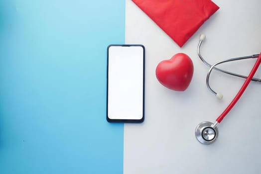 top view of smart phone with empty screen and stethoscope on table .