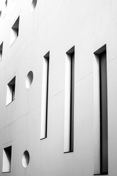 Square and round geometric shaped windows on white stone facade in Spain