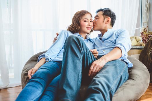 Asian couple having kissing romance on sofa in living room domestic house in Valentines day. Lifestyle and happiness family concept.