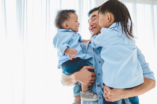 Happy father carrying two children in bedroom at home. Asian family living and having facial expression togetherness. Leisure time. People lifestyle health. Quarantine Covid-19 Coranavirus theme