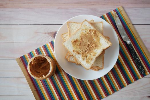 top view of peanut butter and stack of bread on table .