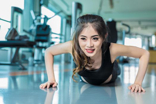 Asian woman fitness girl do pushing ups at fitness gym. Healthcare and Healthy concept. Training and Body build up theme. Strength and Beauty concept