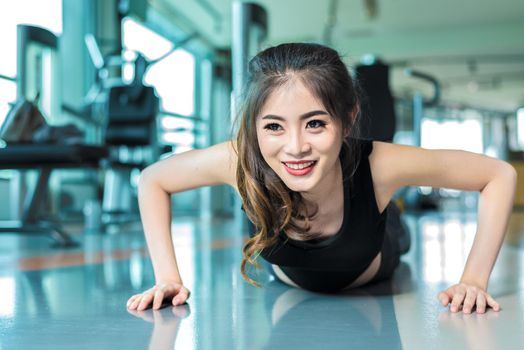 Asian woman fitness girl do pushing ups at fitness gym. Healthcare and Healthy concept. Training and Body build up theme. Strength and Beauty concept