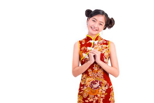 Young Asian beauty woman wearing cheongsam and blessing or greeting gesture in Chinese new year festival event on isolated white background. Holiday and Lifestyle concept. Qipao dress wearing