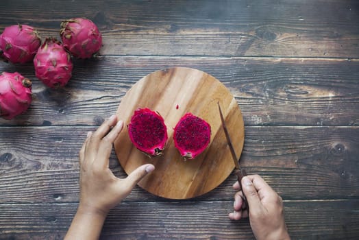 young man cutting a dragon fruit on a chopping board