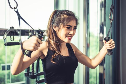 Asian young woman doing elastic rope exercises at cross fitness gym. Strength training and muscular Beauty and Healthy concept. Sport equipment and Sport club center theme. 