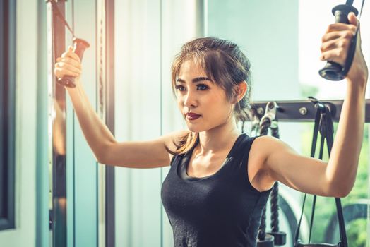 Asian young woman doing elastic rope exercises at cross fitness gym. Strength training and muscular. Beauty and Healthy concept. Sport equipment and Sport club center theme. 