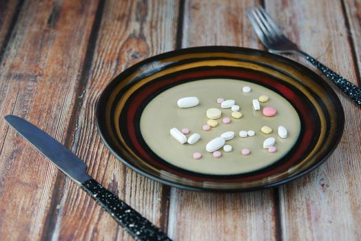 many colorful pills and capsules on plate on table .