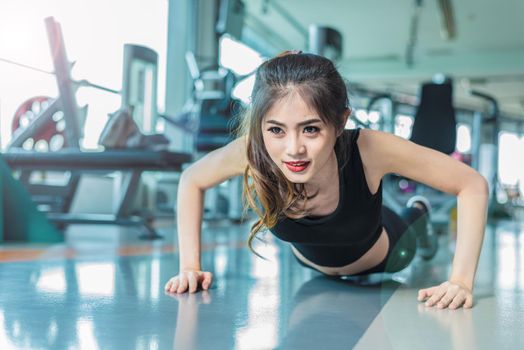 Asian woman fitness girl do pushing ups at fitness gym. Healthcare and Healthy concept. Training and Body build up theme. Strength and Beauty concept