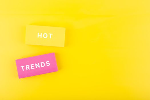 Hot trends written on yellow and pink rectangles on bright yellow background with copy space. Concept of newest, latest, hot and popular trends of 2022