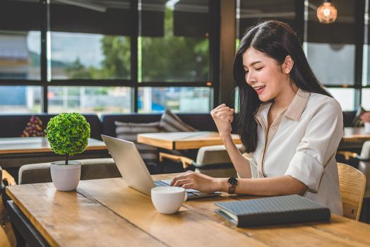 Beauty Asian woman having cheerful gesture after finishing job happily with laptop computer. People and lifestyles concept. Technology and Business working theme. Occupation and coffee shop theme.