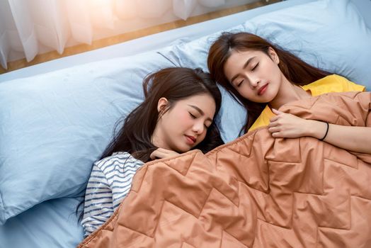 Cute Asian couple women sleeping on bed together. Lifestyles and lovers concept. Happiness life and relax concept. Homosexual and friendship theme. LGBT pride and lesbian theme.