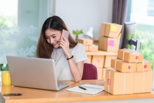 Asian woman enjoy herself while using  internet on laptop and phone in office. Business and marketing and part time concept. Online shopping and business success theme. Happy mood doing working job.