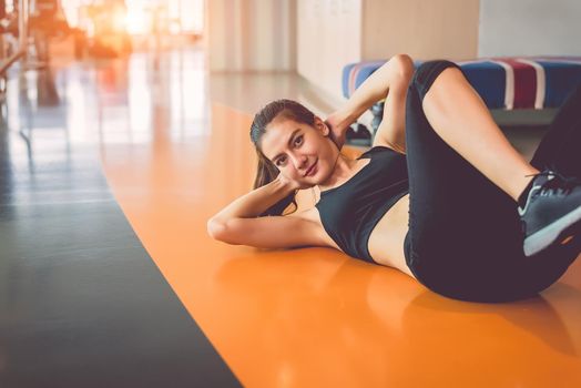 Sport woman doing sit up in fitness sport training club with sport equipment and accessories background. Workout crunch and bodybuilder. Lifestyles leisure and indoors activity. Cardio program concept