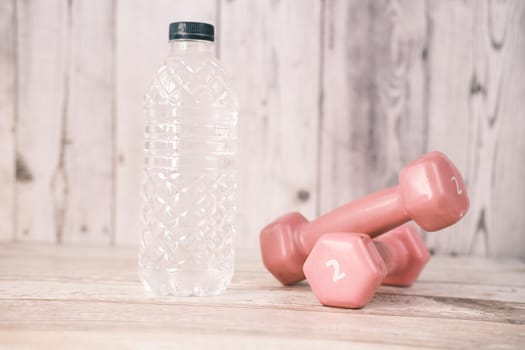 fresh drinking water and a pink color dumbbell on table ,