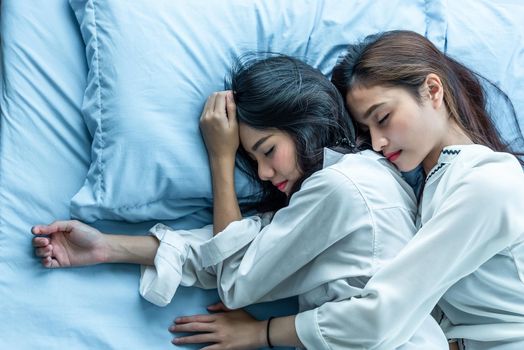 Top view of two Asian women sleeping on bed together. Lesbian lovers and couple concept. People and lifestyles theme.