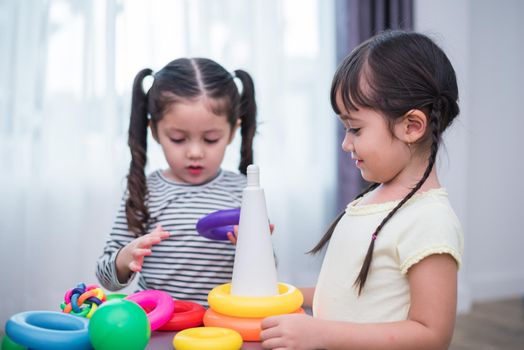 Two little girls playing small toy balls in home together. Education and Happiness lifestyle concept. Funny learning and Children development theme. Smile faces