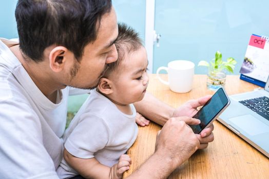 Single dad and son using laptop together happily. Technology and Lifestyles concept. Happy family and baby theme.