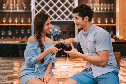 Asian young couples clinking wine glasses at domestic bar of luxury house. Lovers and Couples concept. Honeymoon and Wedding theme. Interior and Dating theme.