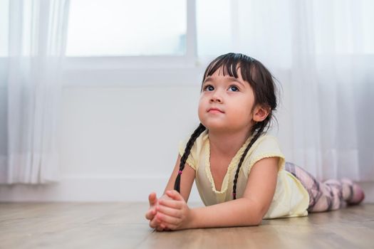 Little girl lying and looking up in home. People and lifestyles concept. Relaxation and Vacation theme. Kids and children theme.