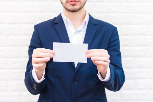 Business man showing white paper. Man  wearing blue suit and holding white blank card. Lifestyle and working concept. Business and object theme. Blank space in paper for insert text.