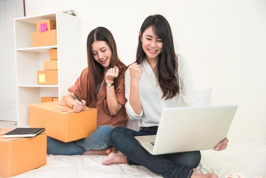 Two young Asian women startup small business entrepreneur SME distribution warehouse with parcel mail box. Owner home office. Online marketing and product packaging and delivery service concept