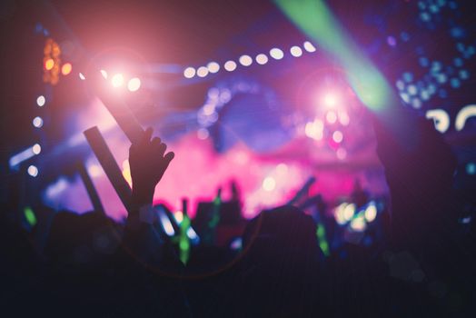 Silhouettes of crowd people in concert bright stage lights. Pink green and purple tone film. Silhouette of hands. People and Entertainment concept. Part of body at outdoors theme.