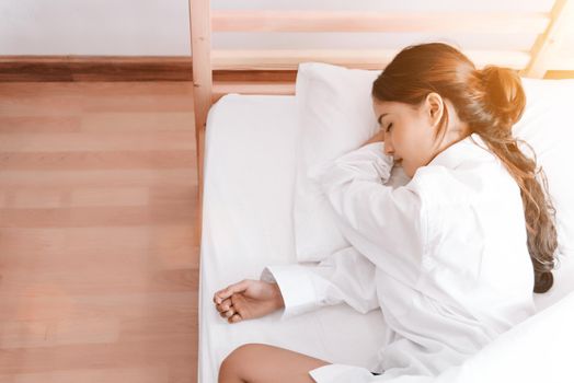 Young Asian woman sleeping on white bed in the morning. Beauty and Holiday concept. Vacation and Relax theme. Interior and People theme. Top view