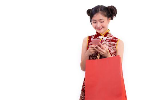 Young Asian beauty woman wearing cheongsam and using smart phone gesture in Chinese new year festival event on isolated white background. Technology and Holiday lifestyle concept. Qipao dress wearing