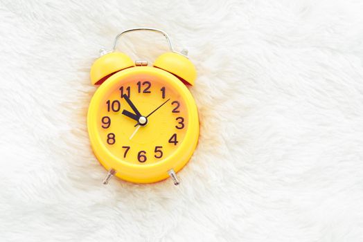 Yellow alarm clock on white wool. Late and Lazy time concept. Morning in holiday theme. Around 10 O Clock