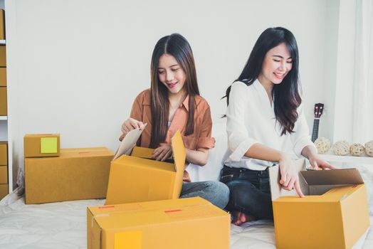 Two young Asian people startup small business entrepreneur SME distribution warehouse with parcel mail box. small  owner home office. Online marketing and product packaging and delivery service