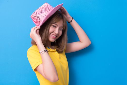 Beauty woman posing with pink hat in front of blue wall background. Summer and vintage concept. Happiness lifestyle and people portrait theme. Cute gesture and pastel tone.