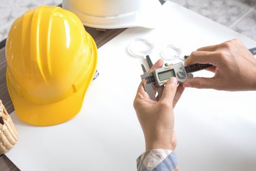 Construction engineer measuring with vernier caliper. Business and Technology concept. Safety helmet and Drawing paper elements. Civil and Drawing sketch theme.