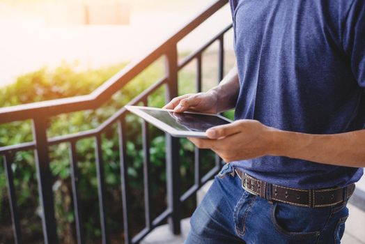 Close up of man hand using tablet while walking at outdoors. Technology and Lifestyles concept. Working people and Gadget theme.