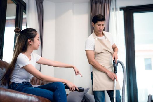Girlfriend force ordering boyfriend to do household work by vacuum cleaner. Lovers and Couples concept. Honeymoon and Wedding theme. Interior and Dating theme. Man dissatisfy to do household working