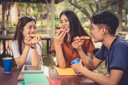 Young Asian people celebrating with pizza in hand. Food and Friendship concept. Lifestyles theme