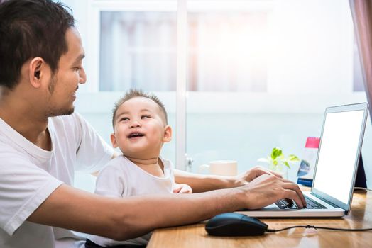 Single dad and son using laptop together happily. Technology and Lifestyles concept. Happy family and baby theme.