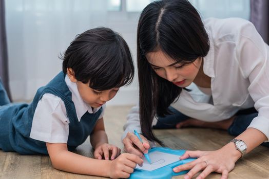 Asian mom teaching cute boy to drawing in chalkboard together. Back to school and Education concept. Family and Home sweet home theme. Preschool kids theme.