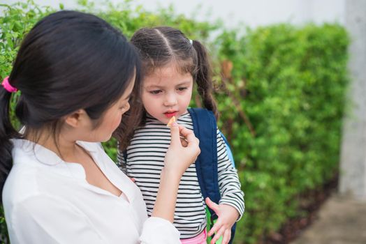 Mom feeding her daughter with snack before going to school. Back to school and Education concept. Home sweet home and happy family theme.