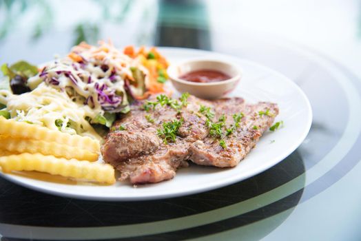 Pork chop steak with salad and gravy sauce in dish. Food and Vegetable concept. Restaurant and menu theme.