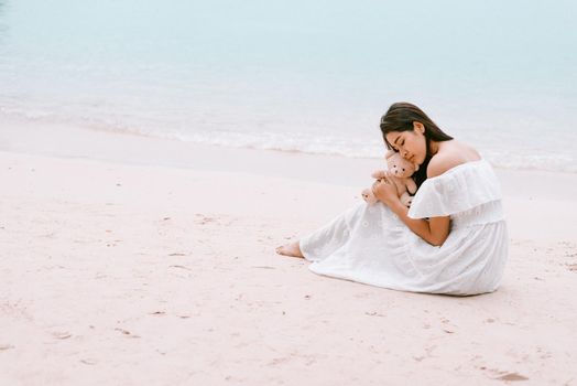 Asian woman hug bear doll and waiting for love that make her happy at beach. Lonely and Beauty concept. Back view scene of girl. Ocean and sea theme. Copy space in left side. Soulmate theme.