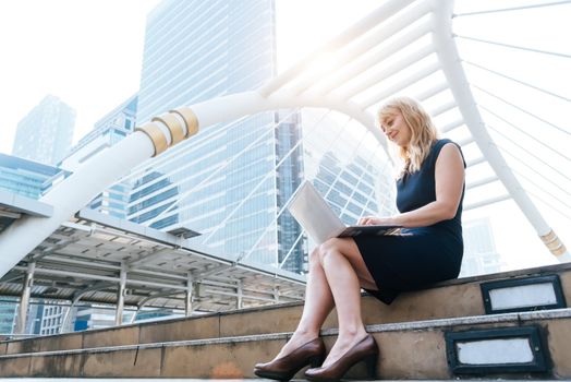 Business woman working with laptop at outdoors. Technology and Happiness concept. Beauty and Lifestyle concept. City and urban theme. Blonde hair woman using computer